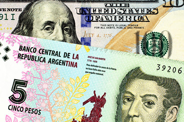 A close up image of a blue, new American one hundred dollar bill close up with an Argentinian five...
