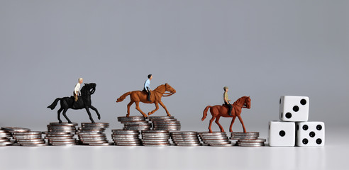 Miniature of horse rider on pile of coins. Concepts about sports gambling and probability of...