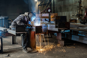 Welding with sparks by Process fluxed cored arc welding ,Industrial steel welder part in factory welder Industrial automotive part in factory.
