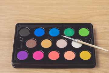 Paintbrush and Watercolor palette on brown wood table.using for Arts and Education background