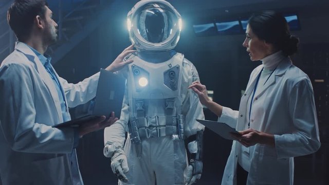 Diverse Team of Aerospace Engineers Design New Space Suit Adapted for Galaxy Exploration and Travel. Group of Scientists Wearing White Coats have Discussion, Use Computers. Constructing Astronaut Suit