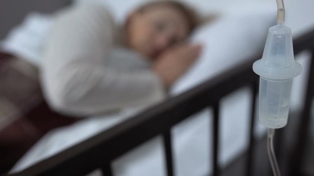 Drop counter closeup, female patient lying in hospital bed, therapy and medicine