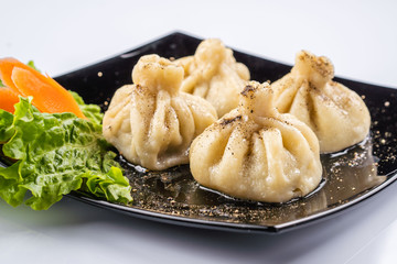 Georgian dumplings Khinkali with meat and red papper, on brown plate