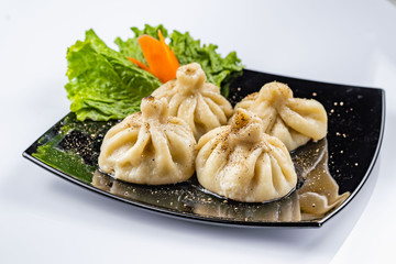 Georgian dumplings Khinkali with meat and red papper, on brown plate