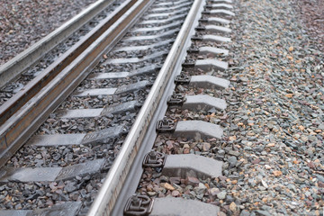 The railway with rusty elements of wear of details and damp stains from a rain , is strewn with sharp stones of rocks , in the afternoon in cloudy weather