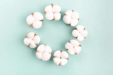 A wreath made from cotton flowers on light green background. Nature and spring concept. Flat lay, top view. Copy space for your text. 