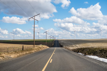 Wind turbines and electric poles along a rural road