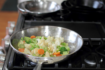Vegetables cooking in a stainless steel pan.