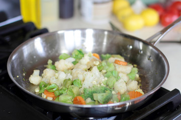 Vegetables cooking in a stainless steel pan.