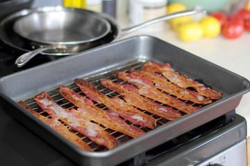 Cooked bacon in a baking tray out of the oven.