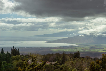 View down the slope of Haleakala of Maalaea Bay and West Maui Mountains as dark clouds form over the Maui valley Hawaii