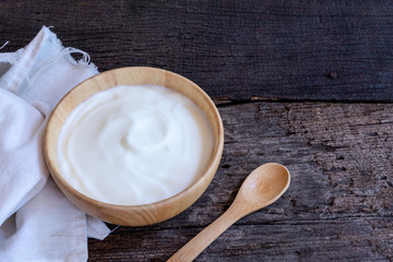 Natural homemade plain organic yogurt in wood bowl on wood texture background