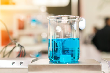 Close up of beautiful vortex blue colorful chemistry liquid in beaker laboratory flask on magnetic stirrer or mixer machine for science