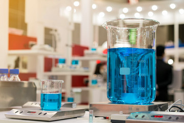 Close up of beautiful vortex blue colorful chemistry liquid in beaker laboratory flask on magnetic...