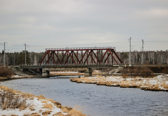 Spring, in some places there is snow, the railway bridge over the river, the village. 