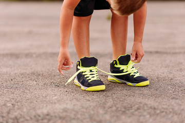 child tying shoelaces on sports shoes in summer