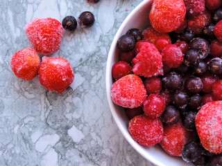 Frozen berries.Top view. Frozen delicious berries on blue background, closeup. Assorted frozen berries background. Raspberries, black currant and strawberries on blue background, copy space.
