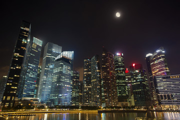 Fototapeta na wymiar Night Sky with Moon above modern skyscrapers architecture. Business city centre skyline in Singapore