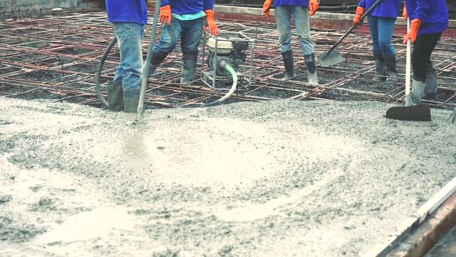 Workers man using a Vibration Machine for eliminate bubbles in concrete. after Pouring ready-mixed concrete on steel reinforcement to make the road by mixing mobile the concrete mixer.