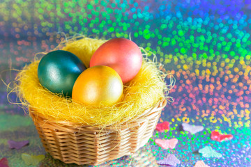 Easter. Multicolored Painted eggs of yellow, pink, green, turquoise pearl color in a basket on a holographic rainbow background with a copy space