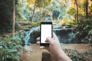 hand holding black smartphone Have space to enter text with white screen at isolated background With a blurred waterfall background