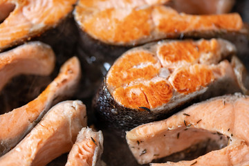Close-up of roasted salmon steaks in a frying pan, top view. Fresh seafood for frying.