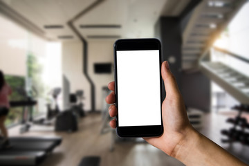 Hand holding white mobile phone with blank white screen  in the gym.