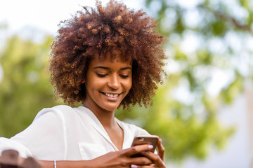 Outdoor portrait of a Young black African American young woman texting  on mobile phone