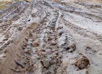 Tires deep tracks on a muddy road. Muddy dirt road in countryside with puddles filled with water and deep tracks from heavy vehicle.