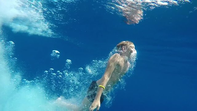 Teenage boy dives into the blue sea.  The boy swims in the Mediterranean sea under water. Slow motion. Mediterranean sea. Clean beautiful sea. 