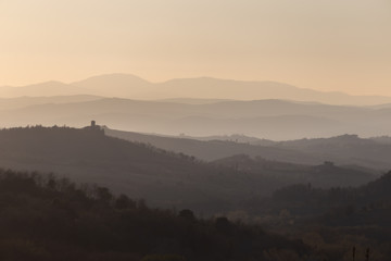 Beautiful view of Tuscany hills at sunset, with mist and warm colors
