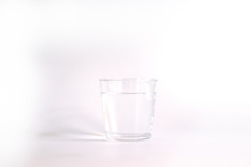 Drinking water in a clear glass on white background.