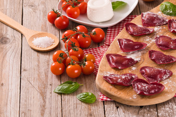 Red heart ravioli with tomato, mozzarella and basil.