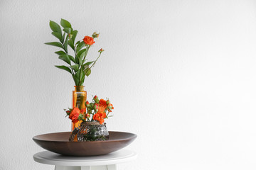 Vases with beautiful flowers on table against white background