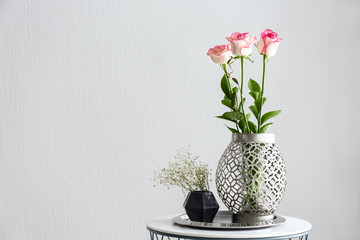 Vases with beautiful flowers on table against white background