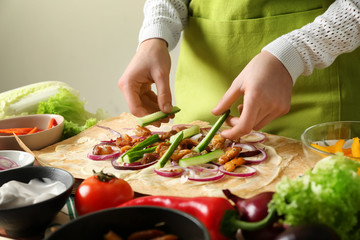 Woman preparing tasty doner kebab on table