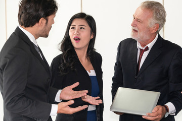 Senior caucasian manager working in office with assistance of young Asian business people and...