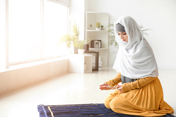 Young Muslim woman praying at home