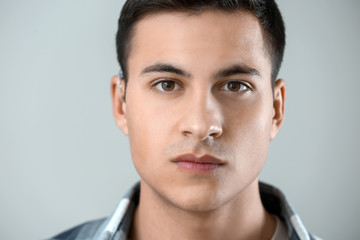 Fototapeta premium Young man with hearing aid on grey background