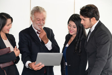 Senior caucasian manager working in office with assistance of young Asian business people and...