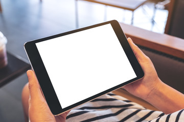 Mockup image of a woman sitting and holding black tablet pc with blank white desktop screen horizontally