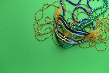 Festive mask with beads on color background