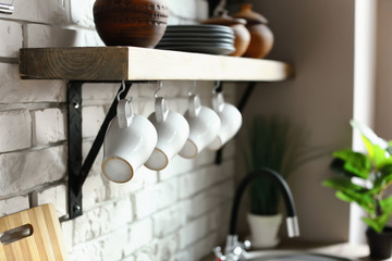 Shelf with set of kitchenware on white brick wall