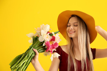 Young woman with bouquet of beautiful tulips on color background