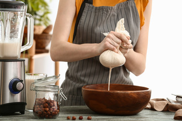 Woman making hazelnut milk in kitchen