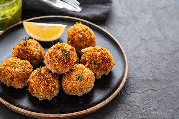 Homemade meatballs with thyme and green sauce on a black plate. Copy space.