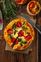 Vegetable pie with broccoli, peas, thyme. tomatoes and cheese on wooden background. Copy space.
