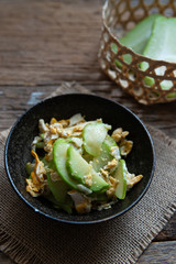 Fresh chayote fruits (Sechium edulis) stir fried with egg and garlic in bowl on wood background