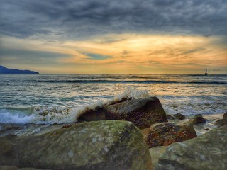 Beautiful sunset view on sea shore with stony background.