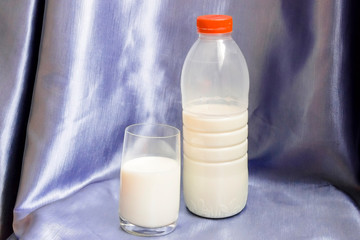 Bottle and glass of milk on blue background.